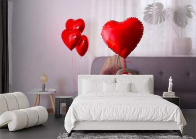 Celebrating Saint Valentine's Day with heart shaped red foil air balloons on the bed. Gift for loved woman on special occasion with romantic symbols, Women`s day. Close up, copy space, background. Wall mural